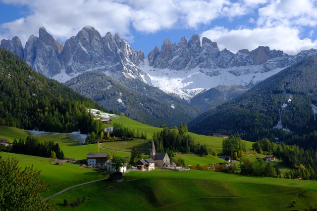 small Italian village with snow-covered mountains of the Dolomites in the background 
