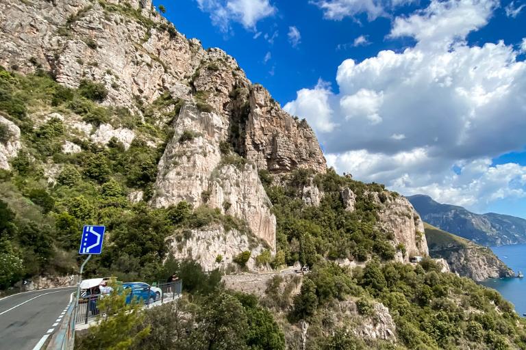 a road with trees and rocks on a hill